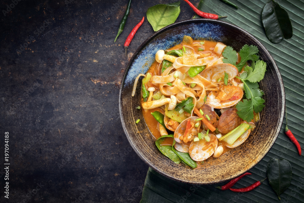 Traditional Thai kaeng phet red curry with clams and vegetable as top view in a bowl with copy space left Traditional Thai kaeng phet red curry with clams and vegetable as top view in a bowl with copy space left