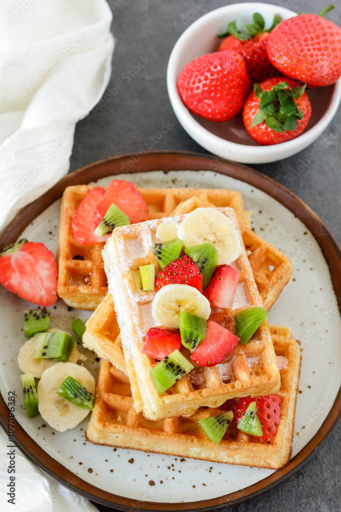 Healthy breakfast table with belgian waffles, exotic fruits and coffee