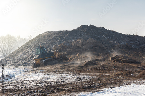 A bulldozer forms a hill on a cold winter day