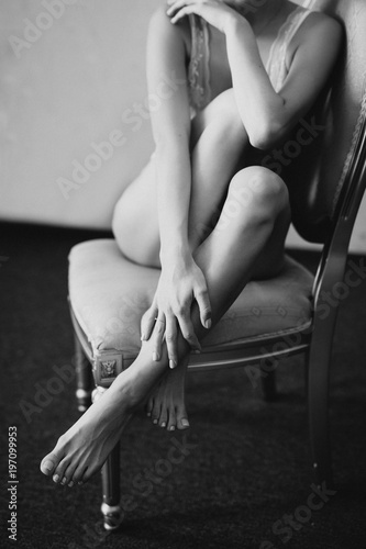 a girl in lingerie sits on a chair and hugs her legs