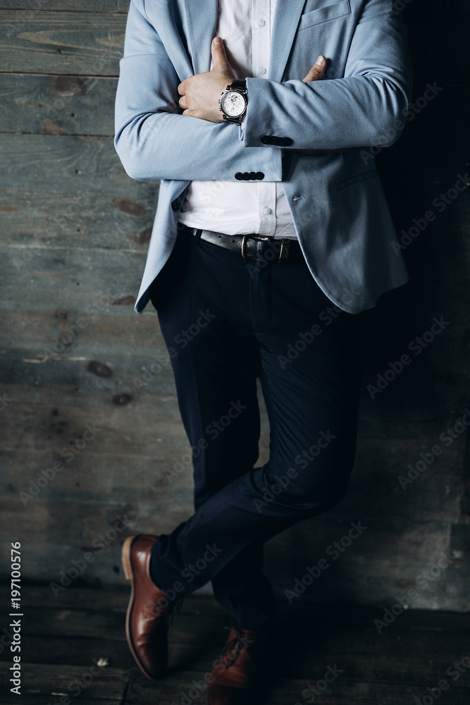 close-up of men's hands in a blue jacket and white shirt and black watches  in black trousers leaned against a wooden wall Stock-Foto | Adobe Stock