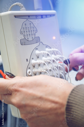 Modern encephalograph and doctor hands with wires in clinic. EEG or Electroencephalography research photo