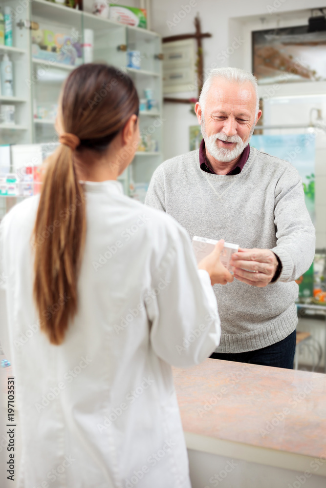 Medicine, pharmaceutics, health care and people concept - Female pharmacist selling medications to senior male customer