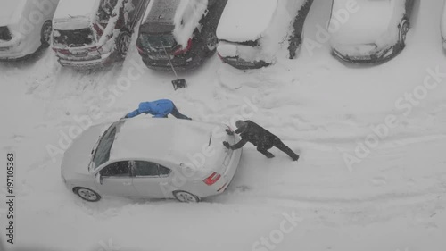 The guys are pushing a car stuck in the snow