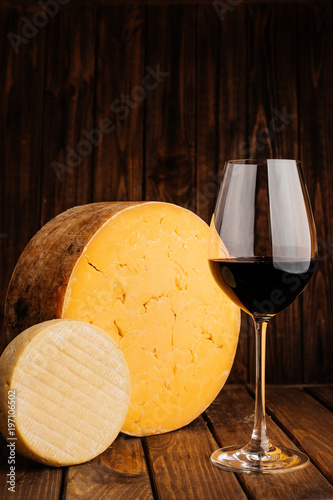 Authentic Crafted Cheese with Glass of Red Wine on Wooden Brown Background.