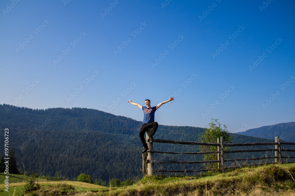 Man with hands up on top of mountains with blue sky. Man enjoying free happiness in beautiful landscape. Travel concept Man with hands up on top of mountains with blue sky. Man enjoying free happiness in beautiful landscape. Travel concept