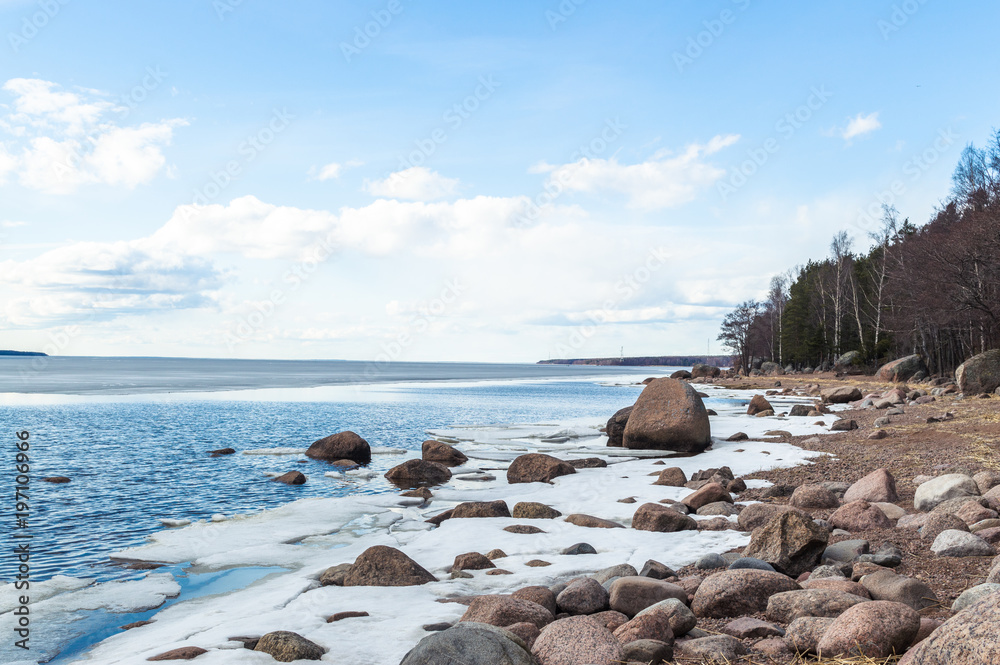 Sunny winter lake shore landscape with now and ice, blue cloudy sky. Ladoga lake