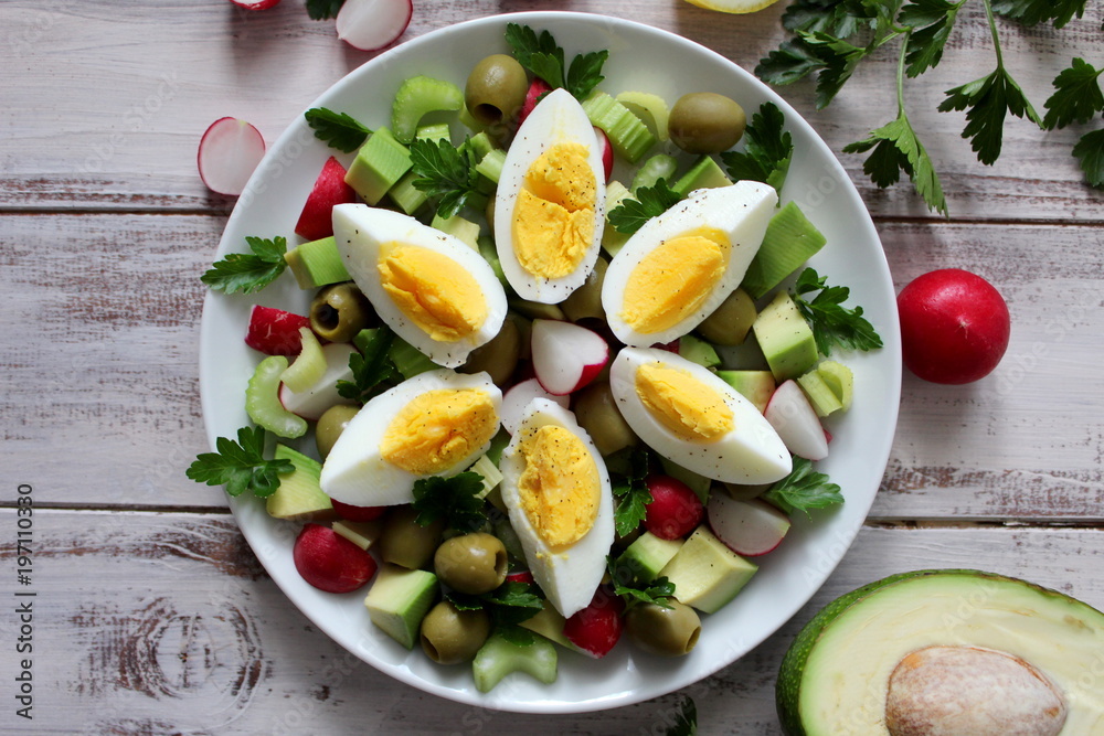 Healthy salad with olive, avocado, celery, raw and eggs on the plate. Top view.