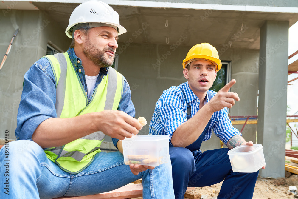 portrait-of-two-construction-workers-taking-break-on-site-eating-lunch