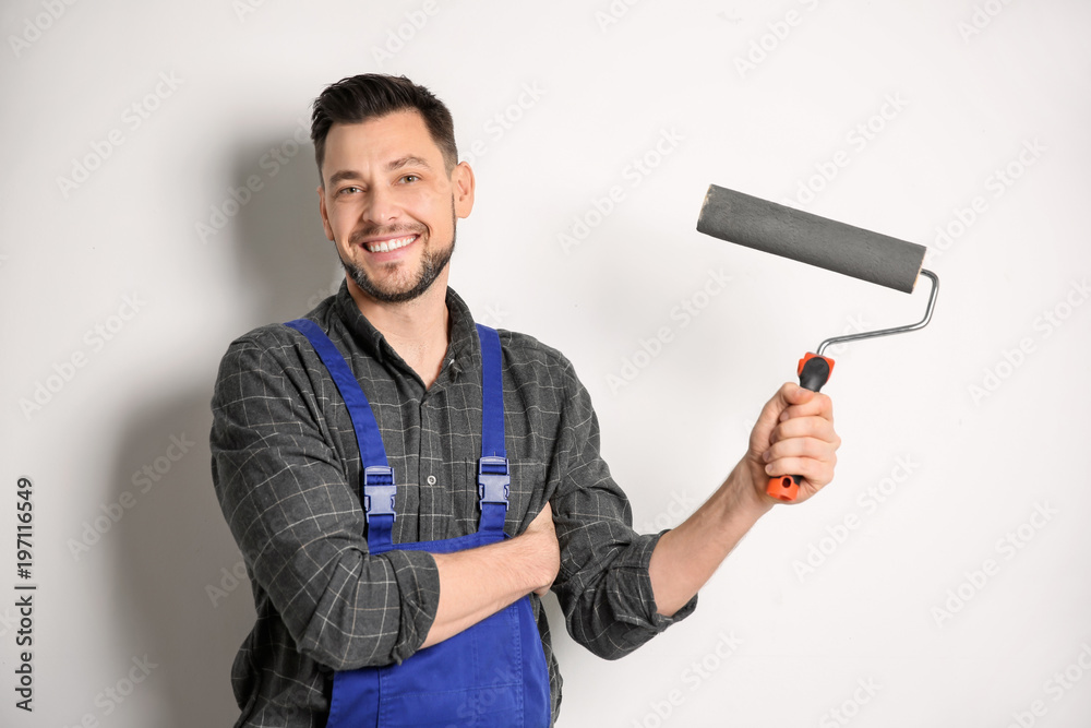 Fototapeta premium Young male decorator with paint roller on white background