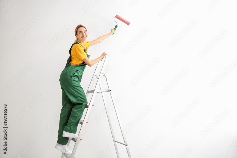 Young female decorator painting wall in empty room Young female decorator painting wall in empty room