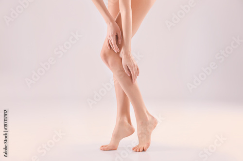 Young woman with beautiful silky skin on light background, closeup of legs
