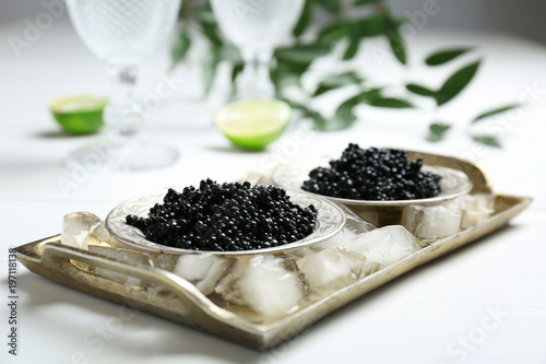 Plates with black caviar served with ice cubes on table