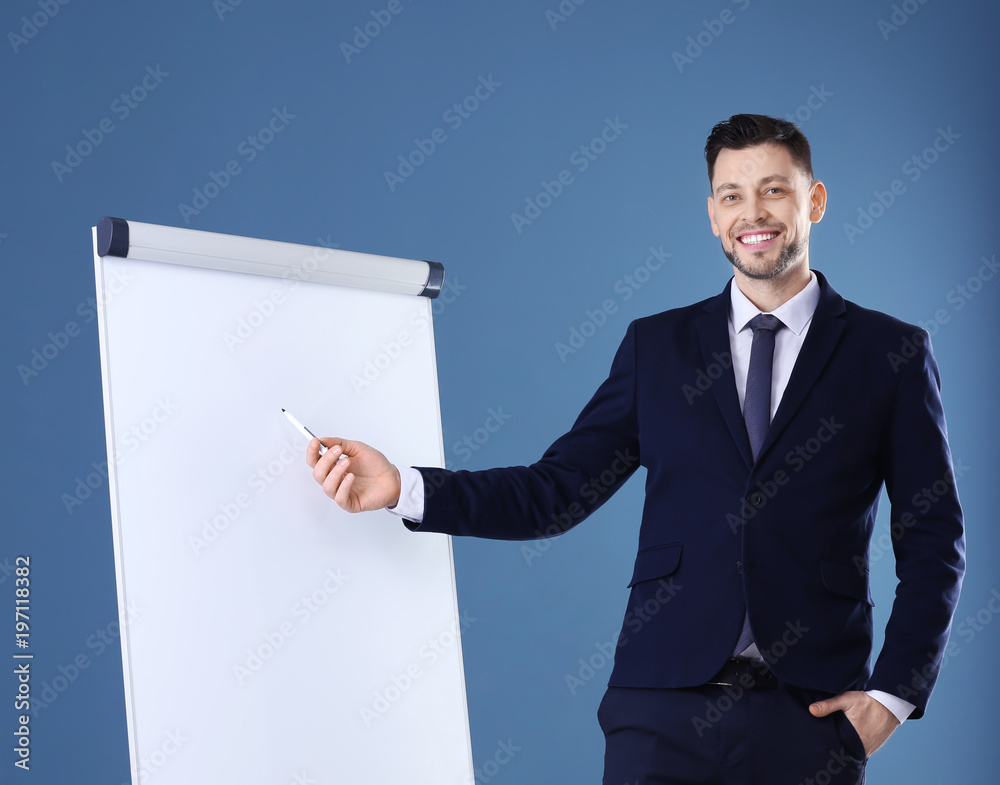 Young business trainer near flip chart on color background Young business trainer near flip chart on color background