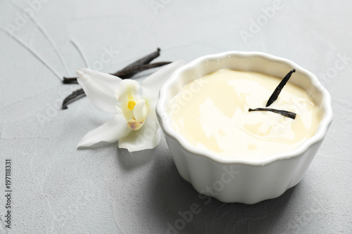 Fotografia Vanilla pudding, sticks and flower on grey background