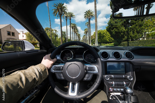 Man driving luxury car in Beverly Hills, California at hot summer day. Luxury lifestyle concept.