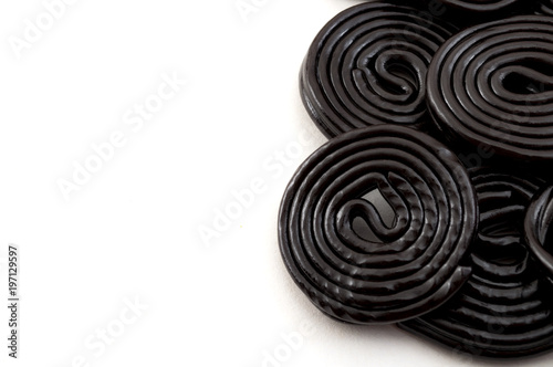 Black liquorice spirals  chewy candy and delicious dessert concept with licorice wheels which are flavoured with the extract of the root of the Glycyrrhiza glabra plant  with copy space