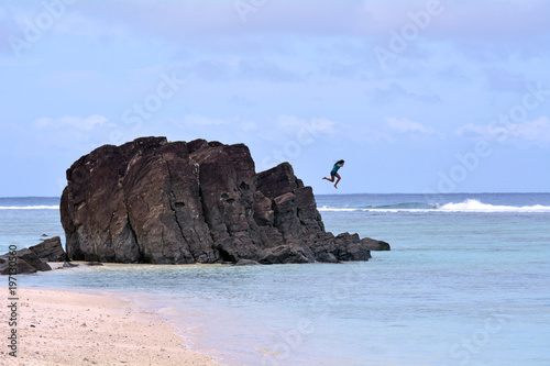 Unrecognizable Cook Islander jumps from the Tuoro (Black Rock) in Rarotonga Cook Islands