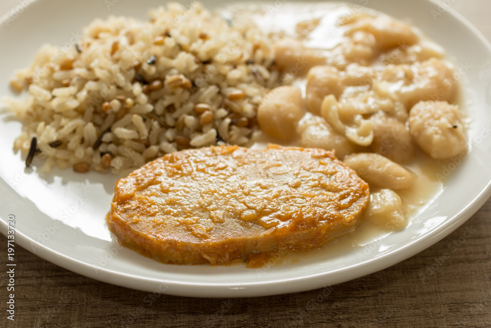 Pork chop, Brown rice and white beans. White dish on wooden table. Detail of food dish, closeup, selective focus. Pork chop, Brown rice and white beans. White dish on wooden table. Detail of food dish, closeup, selective focus.