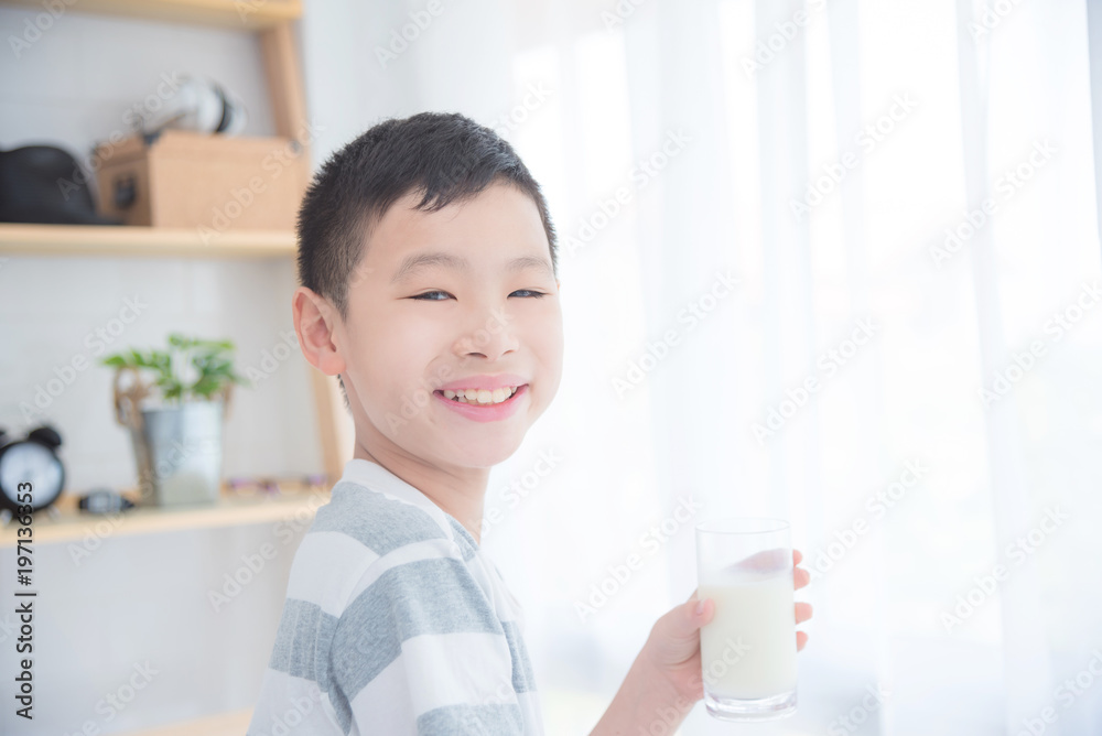 Young asian boy holding a glass of milk and smiling at camera Young asian boy holding a glass of milk and smiling at camera