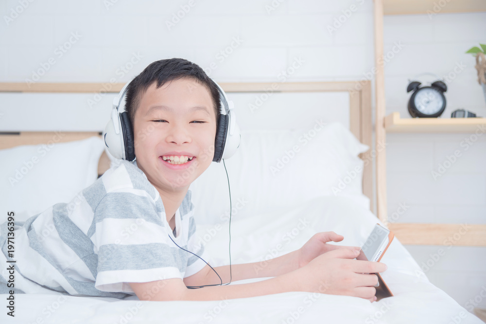 Young asian boy wearing headset while using tablet computer in bedroom Young asian boy wearing headset while using tablet computer in bedroom
