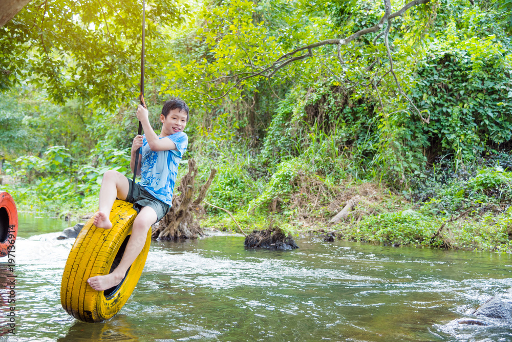 Young asian boy smiling while palying swing chair in the river Young asian boy smiling while palying swing chair in the river