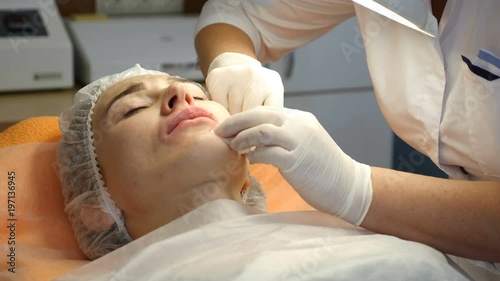 Beauty clinic. Beautician hands in gloves making face aging injection in a female skin. A woman gets beauty facial cosmetology procedure. Botox. collagen injections. Shot in 4k photo