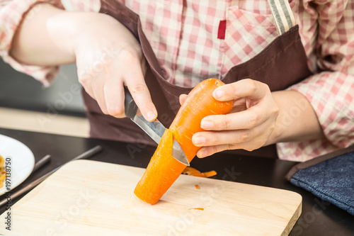 Female cook cutting fresh carrot to make delicious salad