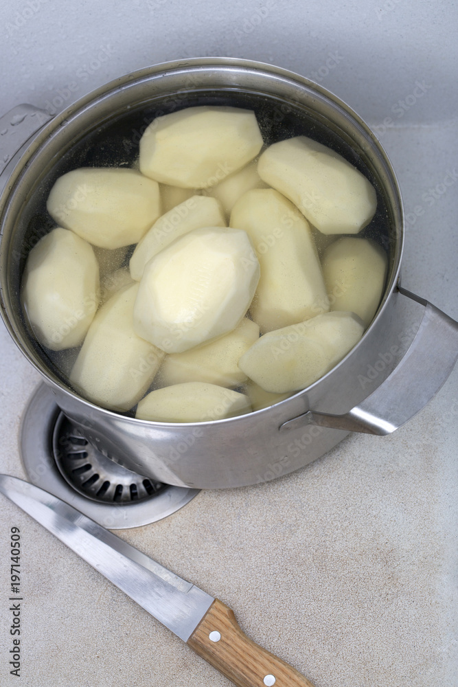 Peeled potatoes in a saucepan in a kitchen sink Peeled potatoes in a saucepan in a kitchen sink