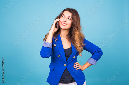 Young smiling business woman talking oh the phone, on blue background