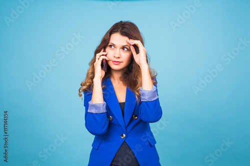 beautiful young woman speaks talking by mobile phone on a blue background