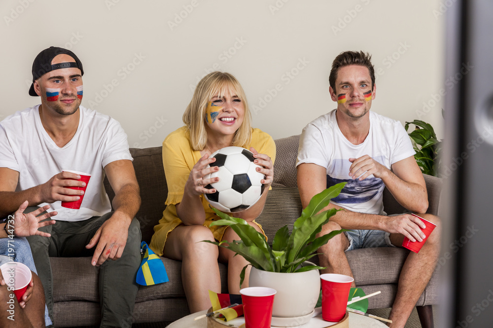 Multinational sports fans watching football on TV with cheer and excitement