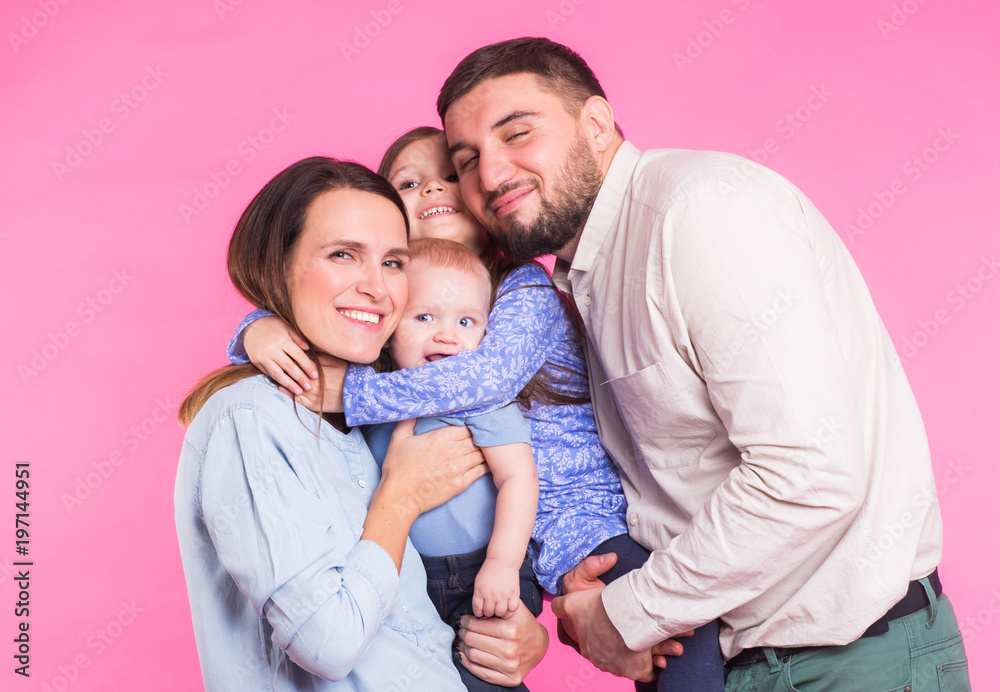 Cute family posing and smiling at camera together on pink background