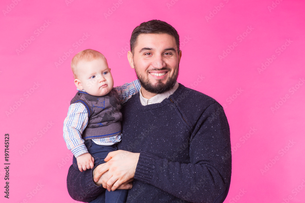 Happy father holding baby son in hands over pink background Happy father holding baby son in hands over pink background