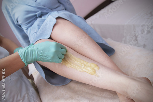 Sugaring Beauty Procedure. Removing Hair on Women's legs. Procedure sugaring in a beauty salon. Sugar depilation. Depilatory sugar paste