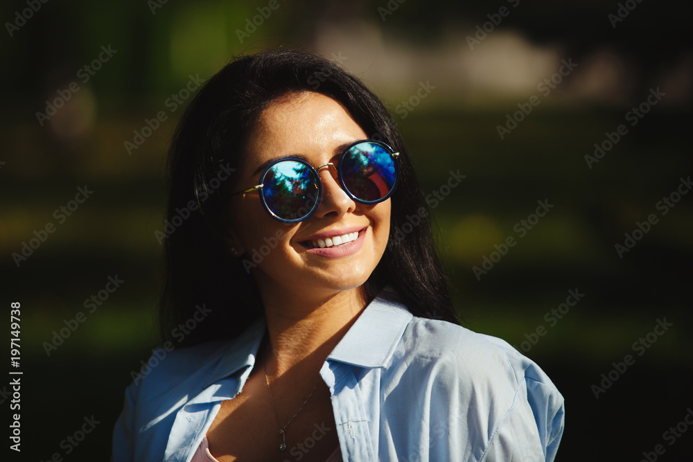 Brunette with dazzling smile in sunglasses looking at the sun. Brunette with dazzling smile in sunglasses looking at the sun.