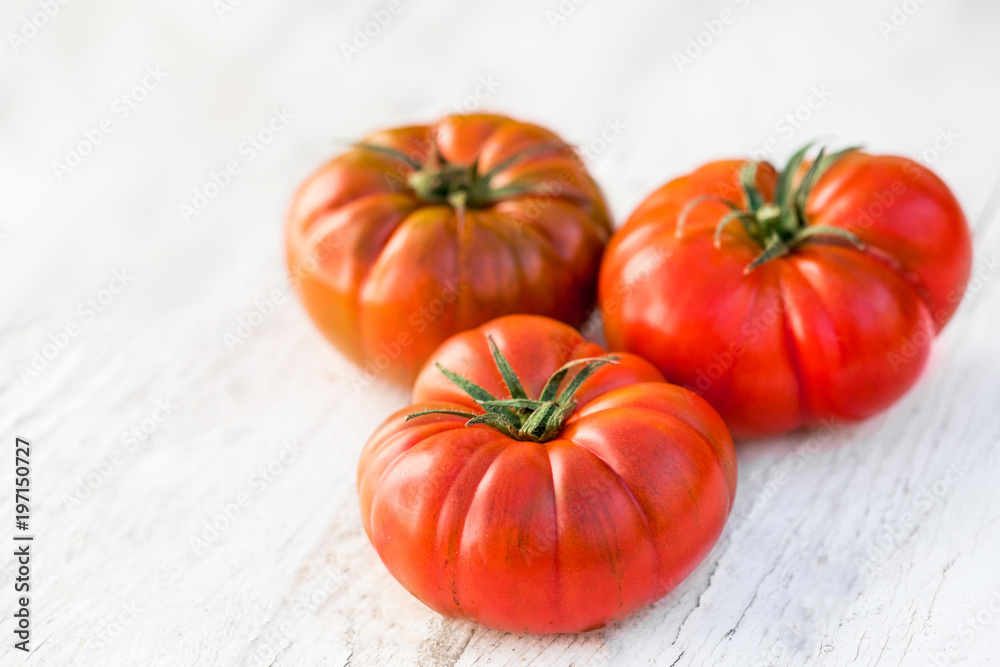 Tomatoes on bright wooden background with copy space. Fresh ripe organic tomatoes on rustic white wood table, top view. Tomatoes on bright wooden background with copy space. Fresh ripe organic tomatoes on rustic white wood table, top view.