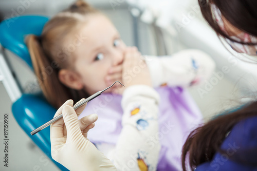 Little child afraid of medical procedure sits in dentist chair