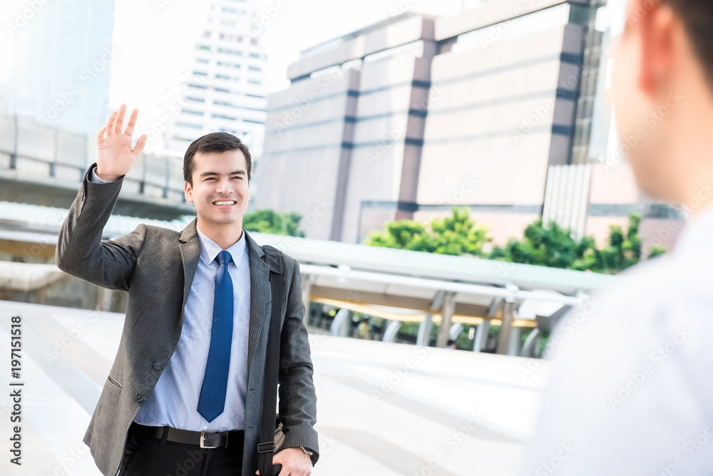 Young handsome businessman waving hand to his friend Young handsome businessman waving hand to his friend