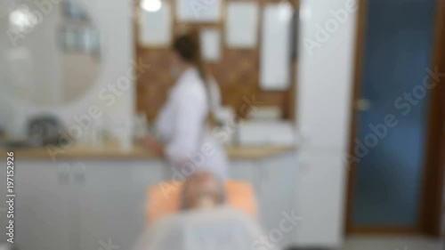 Blurred, defocused, blur video. Beauty clinic. Beautician in gloves making face aging injection in a female skin. A woman gets beauty facial cosmetology procedure. Botox. collagen injections. Shot in photo