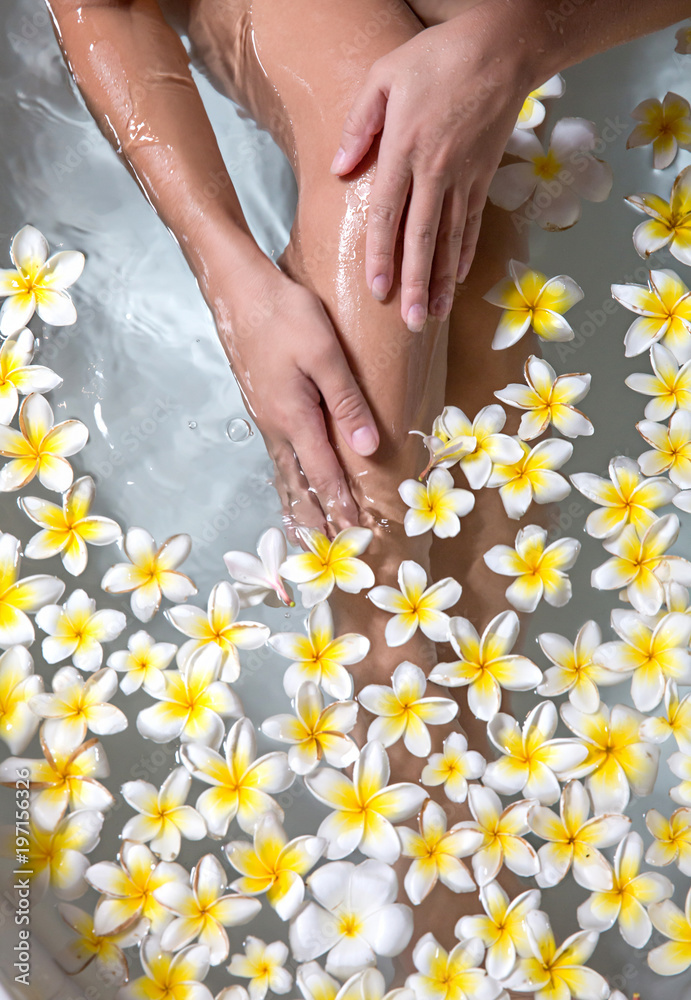 Woman legs in bath tube with flowers spa relaxation body care therapy Woman legs in bath tube with flowers spa relaxation body care therapy