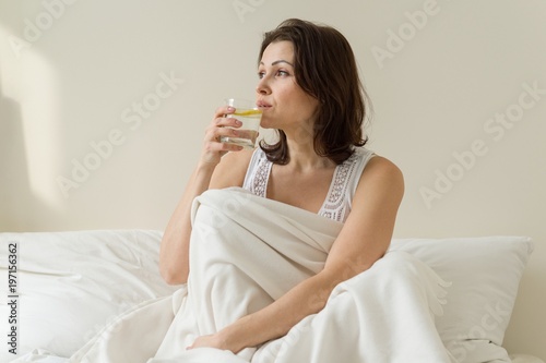 The first morning drink of an adult mature woman is antioxidant - water with a lemon, sitting in bed
