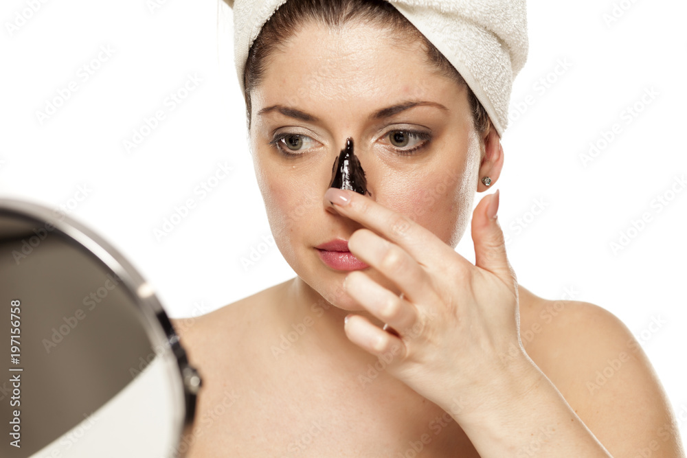 Young beautiful woman with towel on her head applying black mask on her nose Young beautiful woman with towel on her head applying black mask on her nose