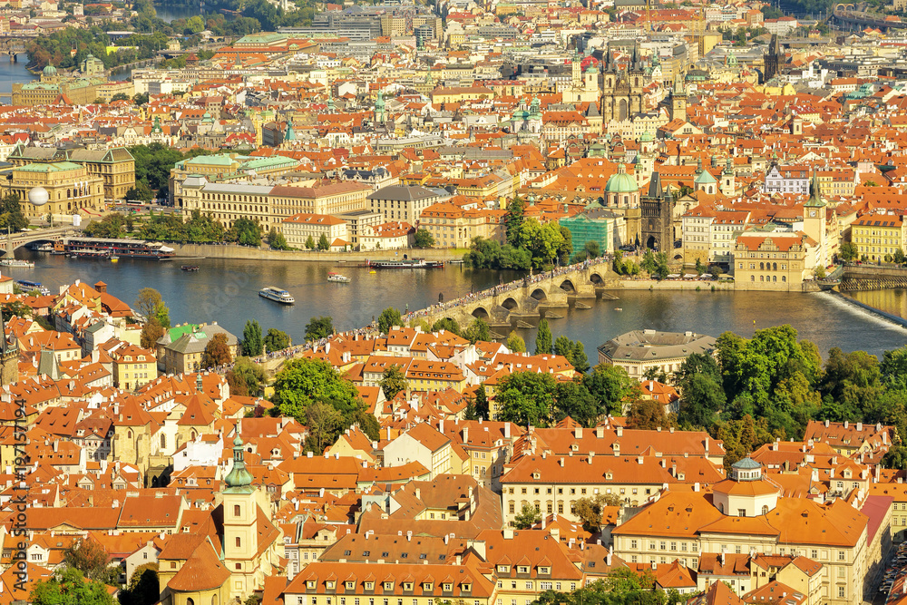 Charles Bridge (Karluv Most) on Vltava river in Prague, Czech Republic. Architecture and landmarks of Prague, cityscape of Prague. Aerial view of houses and roofs of Prague old city town.