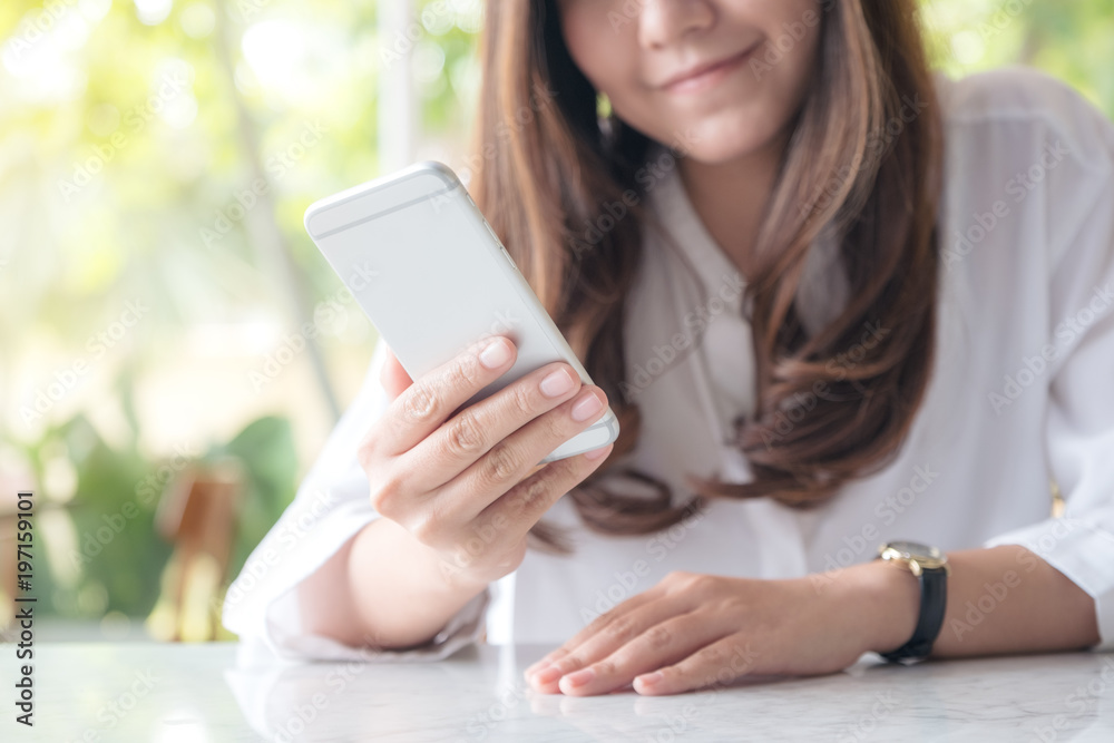 Closeup image of a beautiful Asian woman holding , using and looking at smart phone with feeling happy