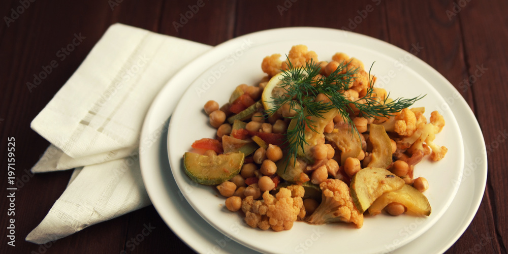 Vegetable stew with chickpeas, cauliflower and cabbages. Organic food. Vegan dish. European cuisine. Vegetarian lunch. Wide photo. Close up.