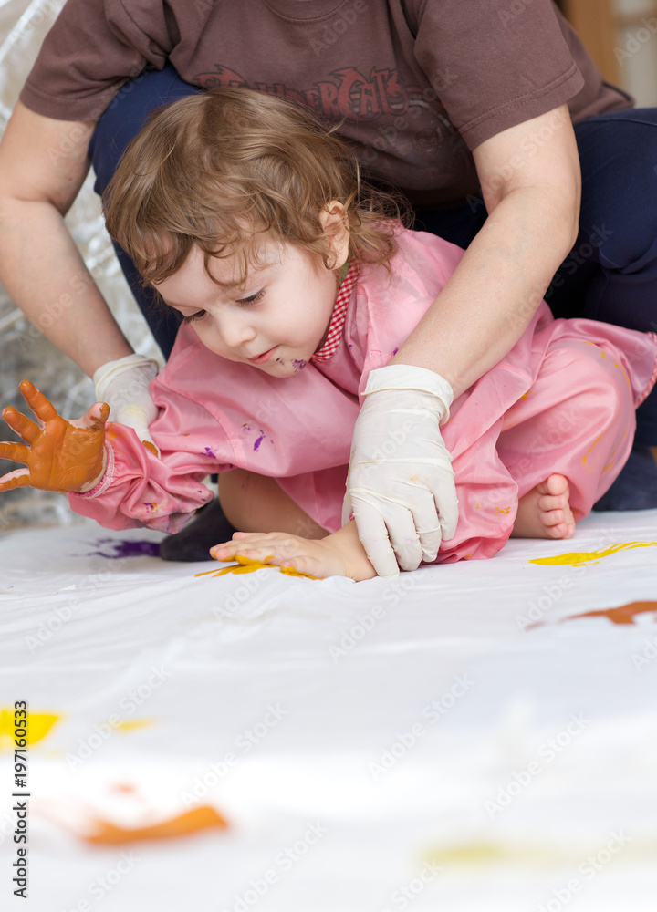 Child is painting white blanket with their palms Child is painting white blanket with their palms