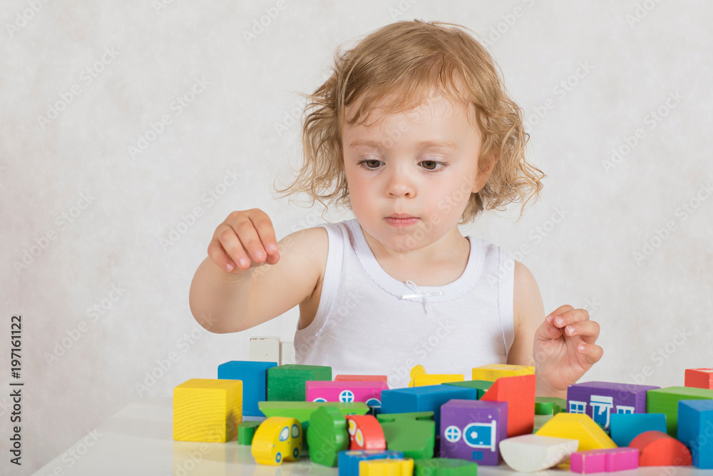 Obraz premium Girl builds up something from colourful geometrical figures and shapes. Closeup