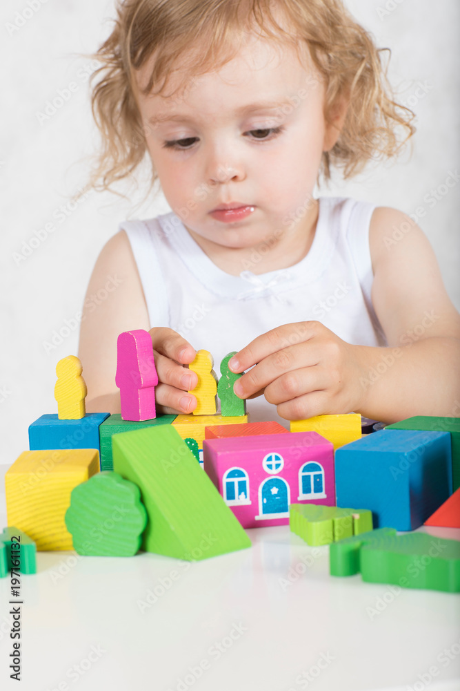 Girl builds up something from colourful geometrical figures and shapes. Closeup Girl builds up something from colourful geometrical figures and shapes. Closeup