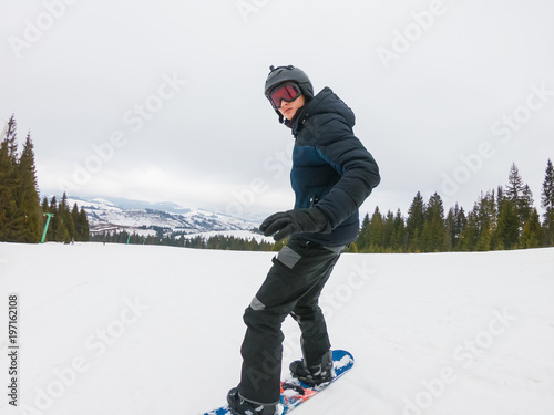 A young man in sports glasses is riding a snowboard in the mountains in Transcarpathia